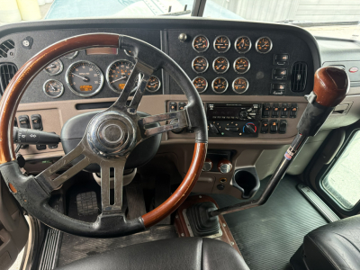 Peterbilt 389 truck dashboard view showing steering wheel, multiple gauges, gear shifter, and control panel.
