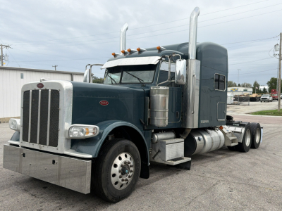 Peterbilt 389 truck in side view with sleeper cab, chrome exhaust stacks, and large chrome bumper. Diesel twin tanks visible, front grille, headlights, and wheels. US-spec truck with dark teal paint.