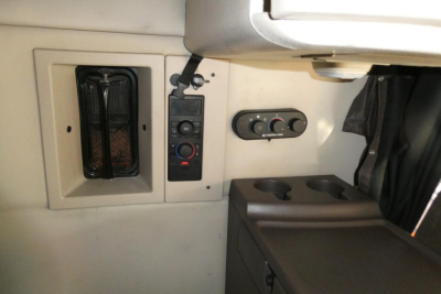 Cab interior of a Volvo truck showing control panel with circular knobs, a small vent, and cup holder area.