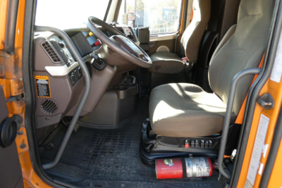 Volvo truck interior cabin with steering wheel and driver's seat, dashboard, and control panel.
