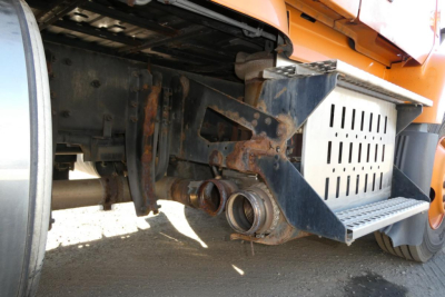 Truck rear undercarriage showing hitch assembly and exhaust components on a Volvo VNM with orange body.