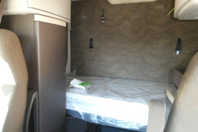 Volvo VNM sleeper cab interior with wall panels and a raised bed in the bunk area.