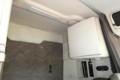Volvo VNM truck sleeper cab interior showing a mounted white refrigerator and control panel.