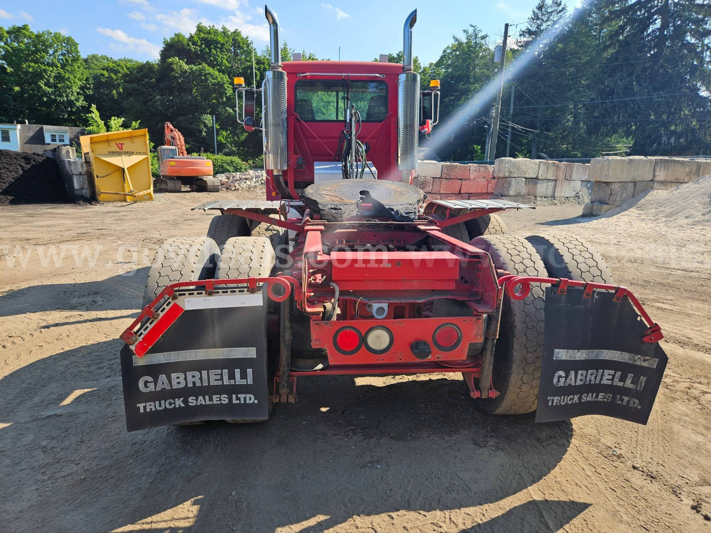Rear view of a red Mack CH613 truck tractor showing dual rear axles, mud flaps labeled GABRIELLI TRUCK SALES LTD, and a fifth wheel with surrounding hydraulic lines.