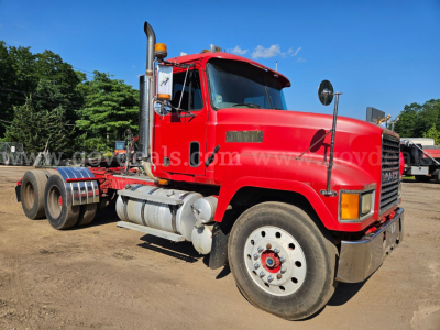 Side view of a red 2003 Mack CH613 truck tractor. Visible text includes a white label on the door and chrome fuel tank; the truck has a large side exhaust, dual rear axles, and large front wheel with a red hub.