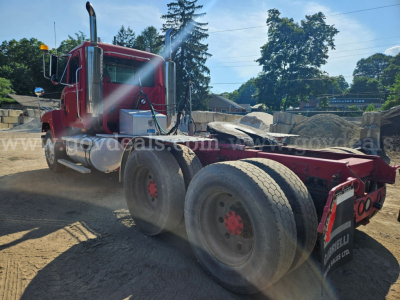 Truck chassis of a red 2003 Mack CH613 showing rear dual-axle configuration with mud flaps, exhaust stack, and visible tires.
