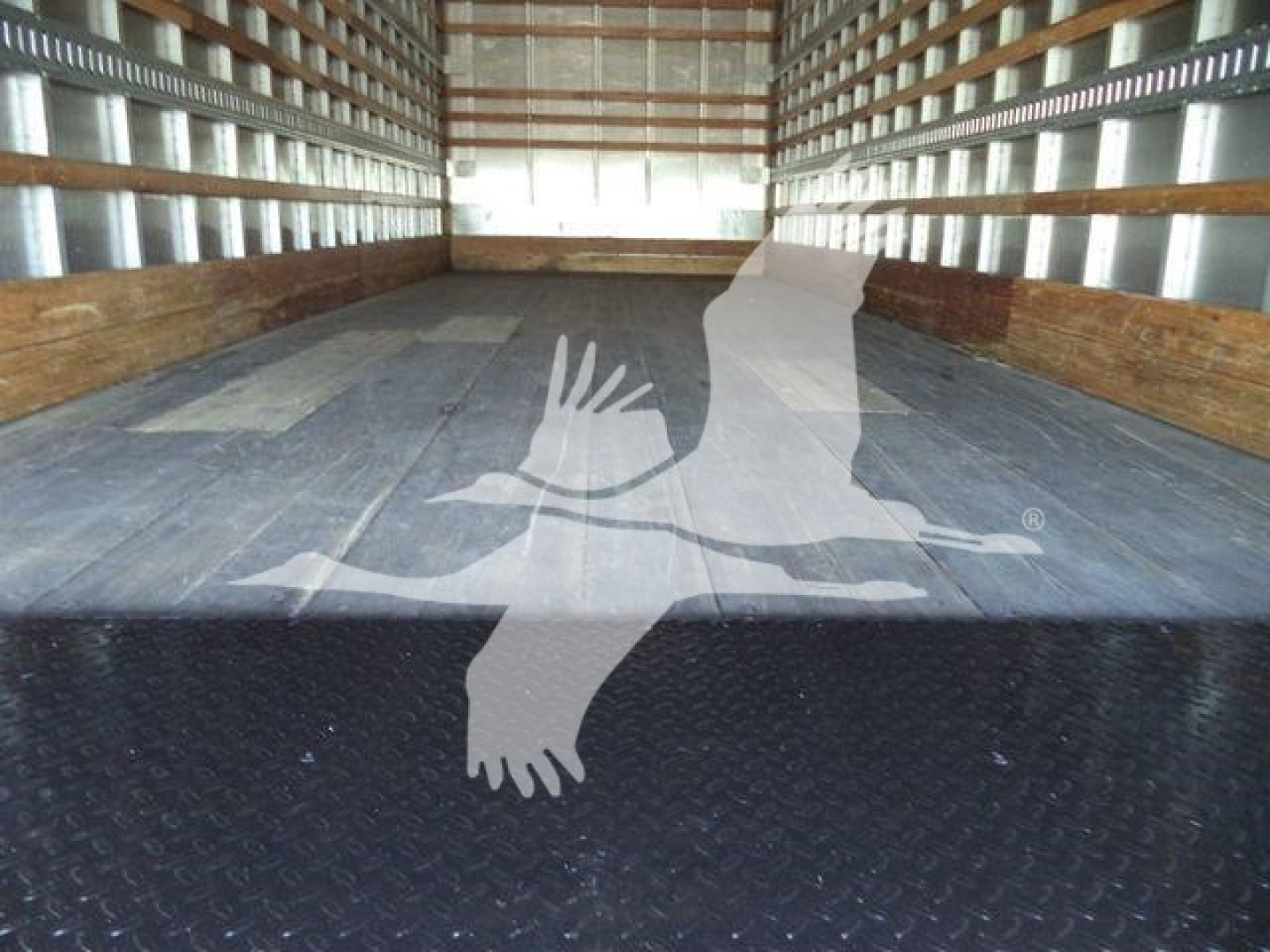 Truck cargo bed of a new 2026 Mack MD6 box truck showing empty flat steel floor and side walls.