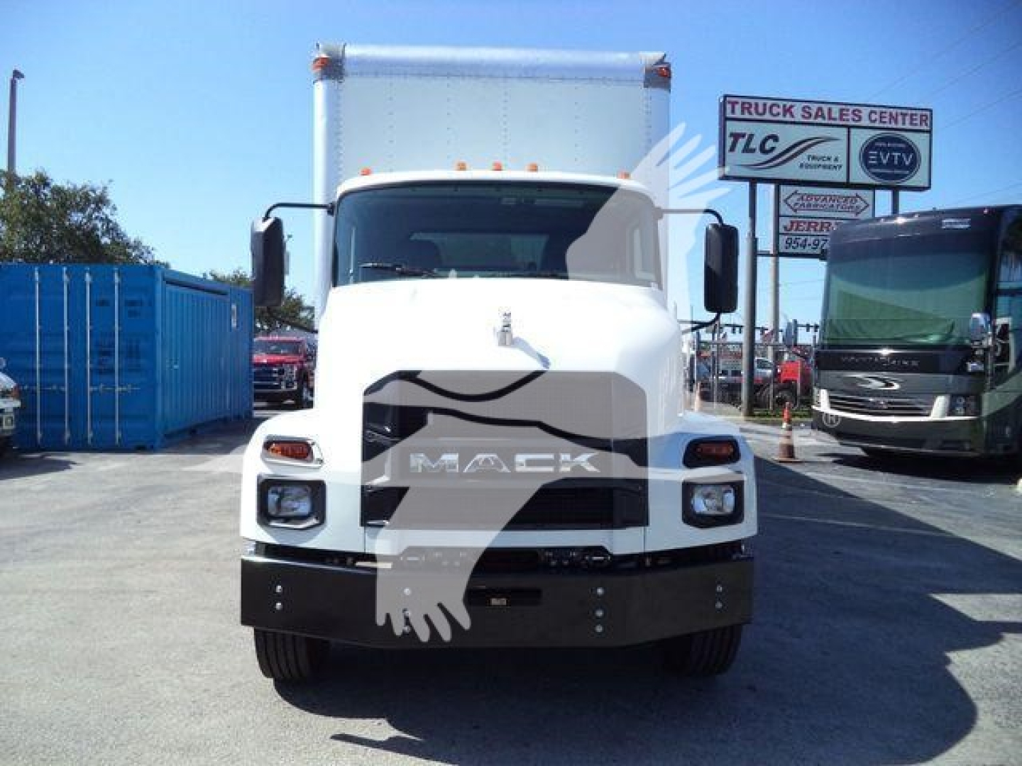 Front view of a white 2026 Mack MD6 box truck showing cab and cargo area, with dealership signage in background.