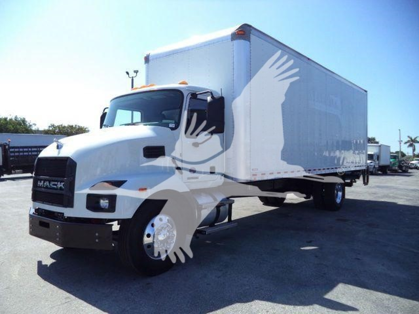 Box truck in a dealership lot showing Mack MD6 cab and a large box trailer.