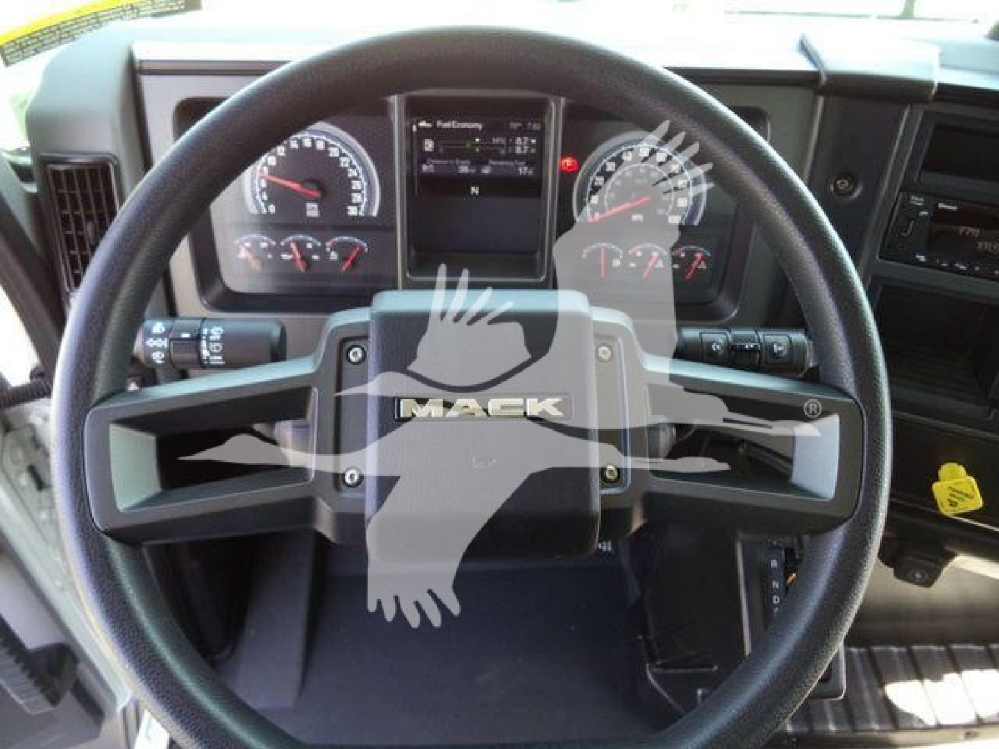 Mack MD series truck cockpit with steering wheel and dashboard gauges visible.