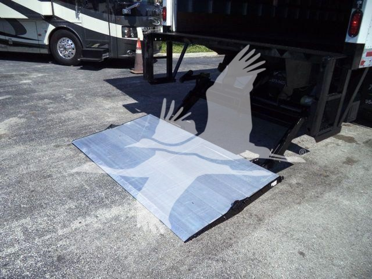 Truck liftgate and platform for a 2026 Mack MD6, with loading ramp extended under rear of truck bed.