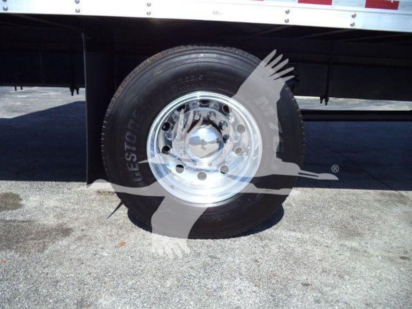 Truck wheel and tire with chrome hubcap mounted under a Mack MD6 box truck. Visible text includes 'Goodyear' on tire and general wheel area; no other legible specifications.