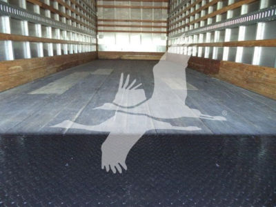 Truck cargo bed of a new 2026 Mack MD6 box truck showing empty flat steel floor and side walls.