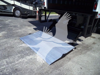 Truck liftgate and platform for a 2026 Mack MD6, with loading ramp extended under rear of truck bed.