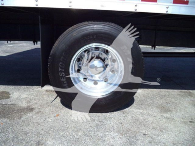 Truck wheel and tire with chrome hubcap mounted under a Mack MD6 box truck. Visible text includes 'Goodyear' on tire and general wheel area; no other legible specifications.