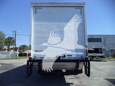Rear view of a new Mack MD6 box truck with a large white graphic of a bird in flight on the rear doors.