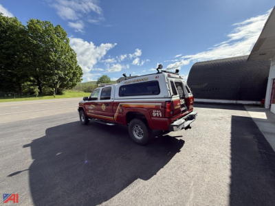 Chevrolet 2500HD emergency pickup truck with cap, rear view angled in parking lot, fire/EMS livery red with white cap, 4x4 badge, lettering on doors