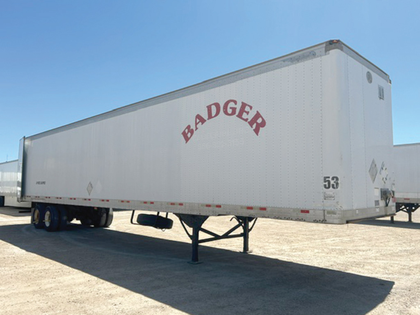 Great Dane P-Series trailer with Badger logo in red on white sides, parked on a dry lot, front landing gear visible.