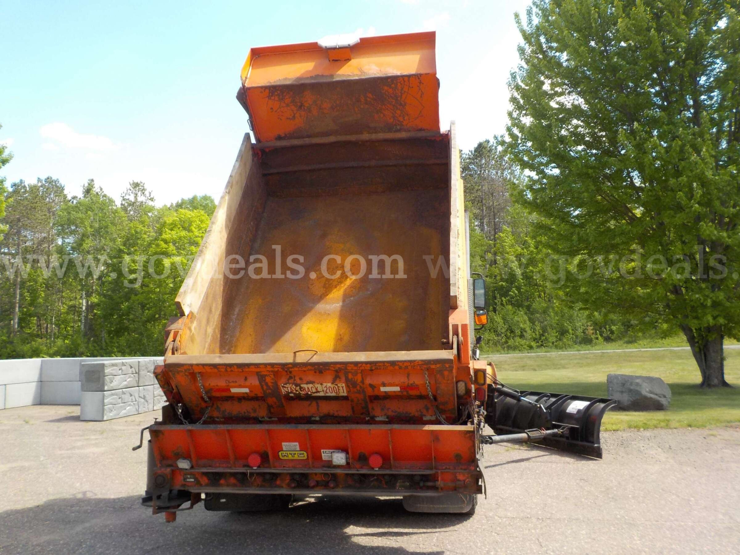 Truck bed of a 2009 International 7400 plow truck with rear hopper open, orange and black colors, in-side view.