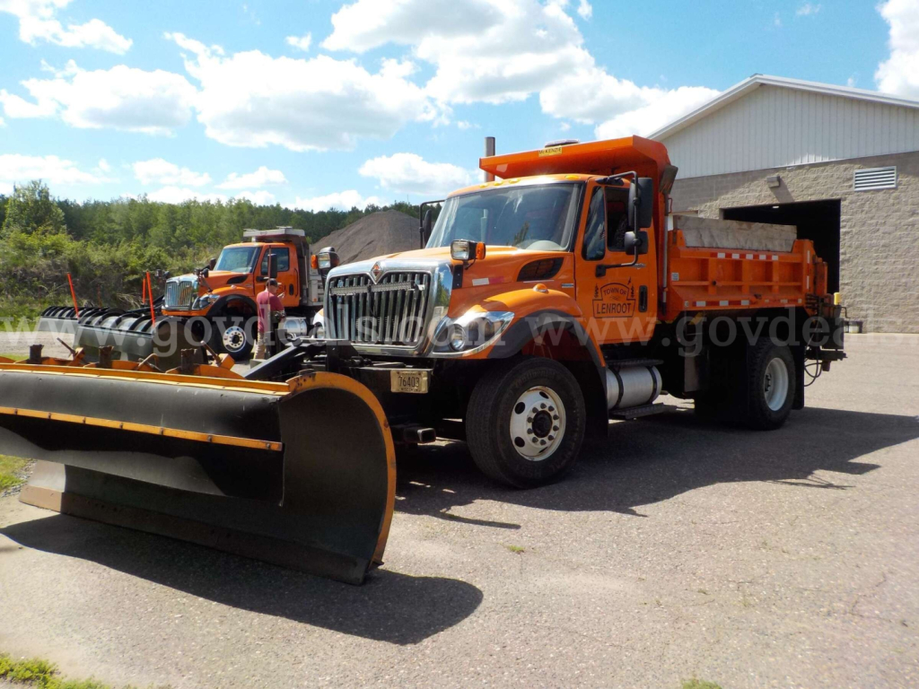 Orange International 7400 dump truck with snow plow in front and another plow truck in background.