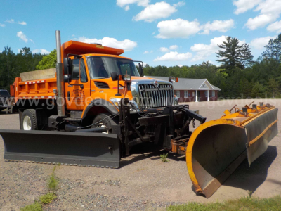 Front and side view of an orange 2009 International 7400 dump truck with a front plow and a snowplow blade attached.