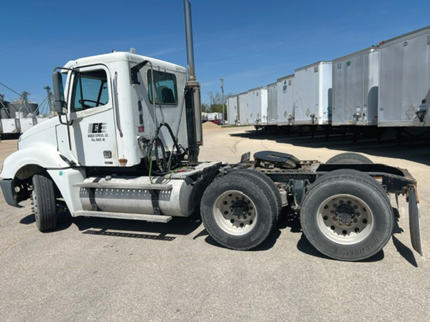 Tractor unit side view of a 2006 Freightliner CL120 Columbia conventional daycab showing dual rear axles, fuel tanks, and cab with bunk window.