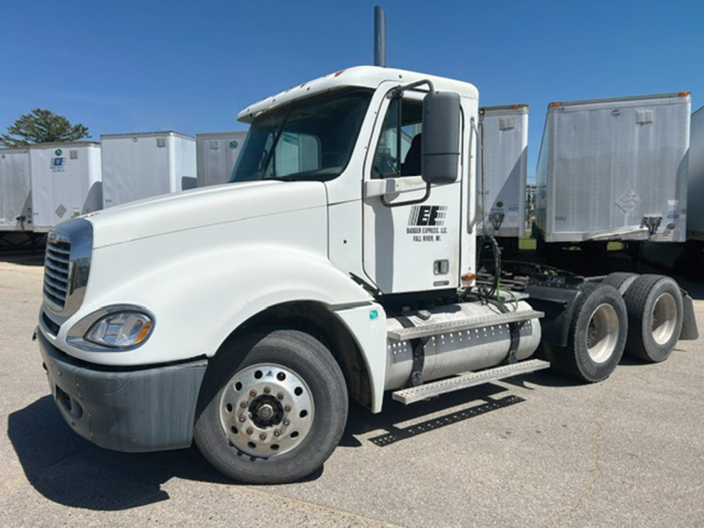 Truck cab side view showing Freightliner CL120 Columbia with white exterior and dual rear axles, fuel tank, and steps.