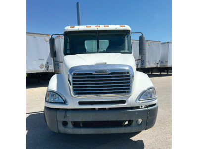 Front view of a white 2006 Freightliner CL120 Columbia sleeper cab truck showing grille, headlights, bumper, and windshield; trailers in background.