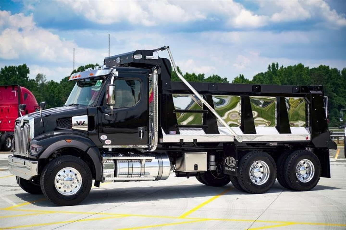 Western Star 47X dump truck side view showing black cab and aluminum dump bed, chrome fuel tanks, and dual rear axles.