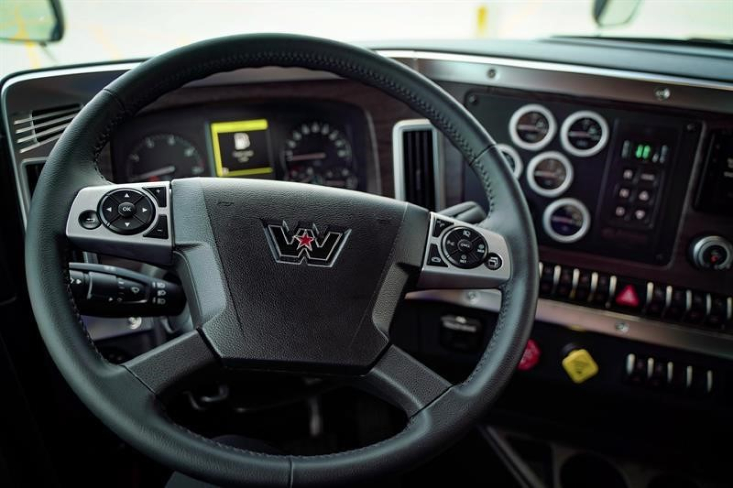 Inside view of a Western Star truck cabin showing steering wheel with Western Star logo and instrument cluster dashboard.
