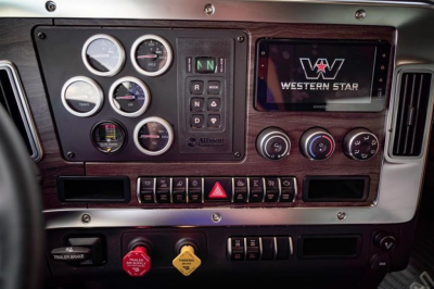 Dashboard and instrument cluster of a new Western Star 47X dump truck showing gauges, digital screen with Western Star logo, and control switches.