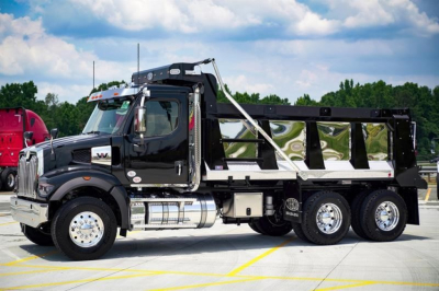 Western Star 47X dump truck side view showing black cab and aluminum dump bed, chrome fuel tanks, and dual rear axles.