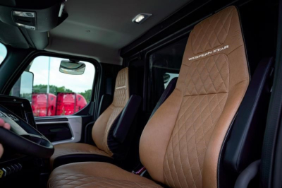 Truck interior showing tan quilted leather seats with WESTERN STAR branding on headrest; dashboard and driver area visible.
