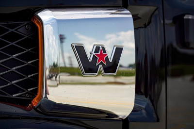 Close-up of a Western Star emblem on a chrome grille, reflecting the surroundings.
