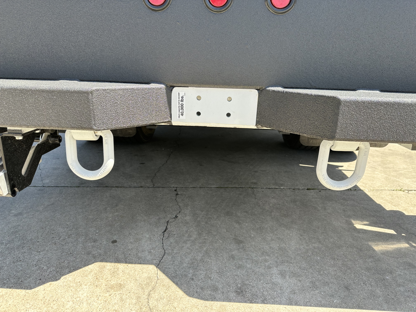 Rear view of new Mack MD7 service/truck showing bumper, hitch mounts, and central white plate with small label.