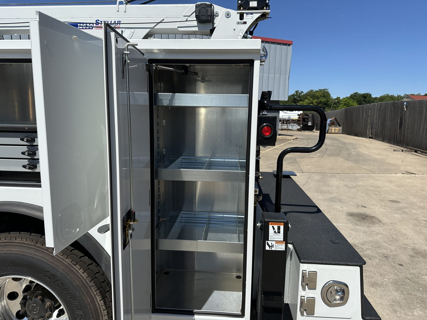 Mack MD7 service truck side cabinet open showing empty metal shelves.