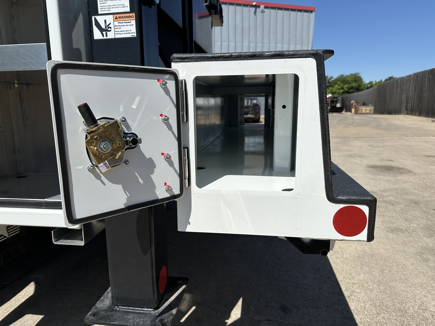 Service/utility truck with a storage compartment door open, showing a white interior cavity and a mounted brass lock mechanism on the inner door.