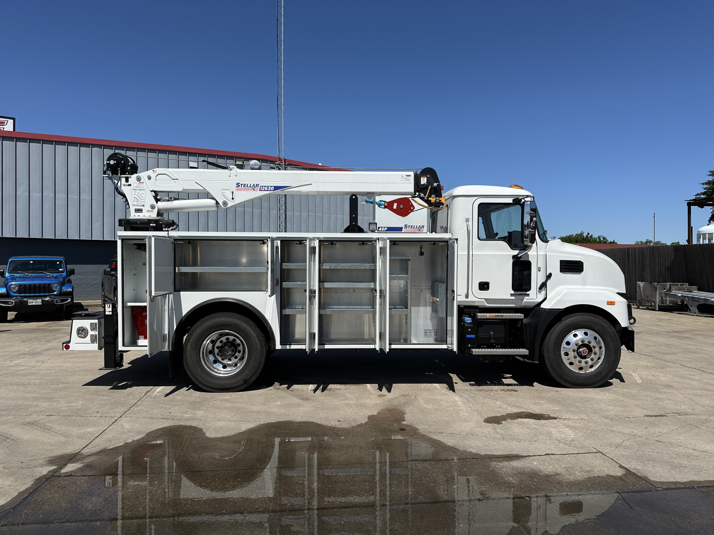 Mack MD7 service truck with boom lift side view showing utility body and stabilizers.