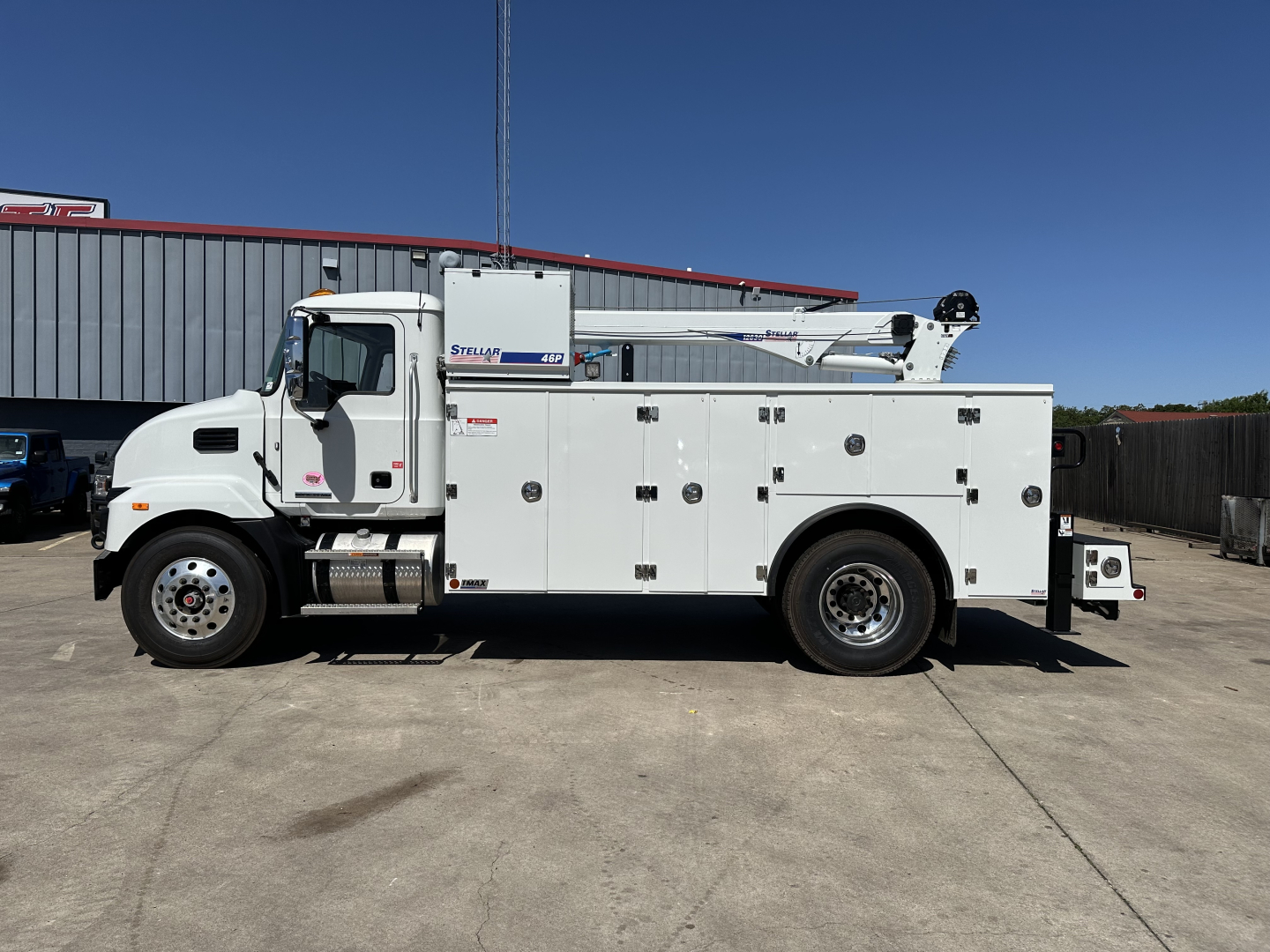 Service/Utility truck body shown in side view; white cab and utility/service compartments with multiple access doors; boomed equipment mounted on body; Mack MD7 likely badge on door.
