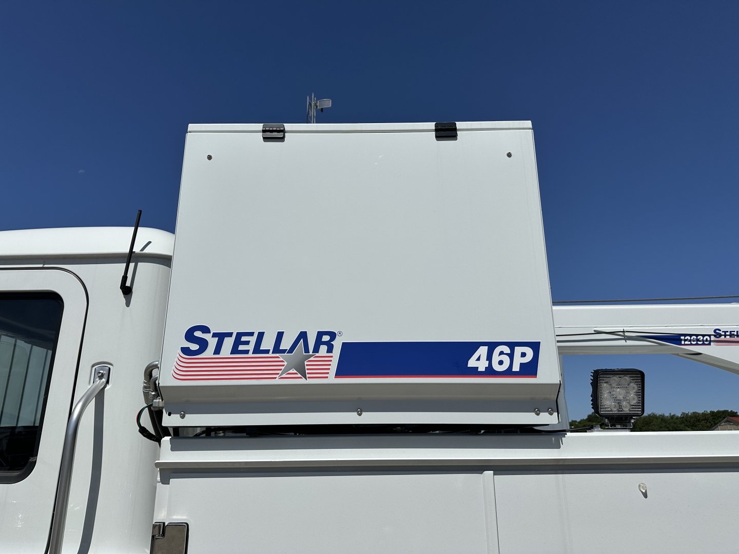 Truck cab area with Stellar 46P refrigeration unit mounted on top of chassis, white exterior, clear blue sky.