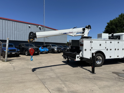 Mack MD7 service truck with crane arm extended, utility body in a parking lot.
