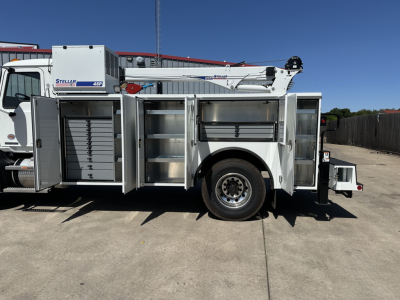 MD7 service truck side view with multiple tool compartments open and a mounted crane, rack storage, and wheel visible.