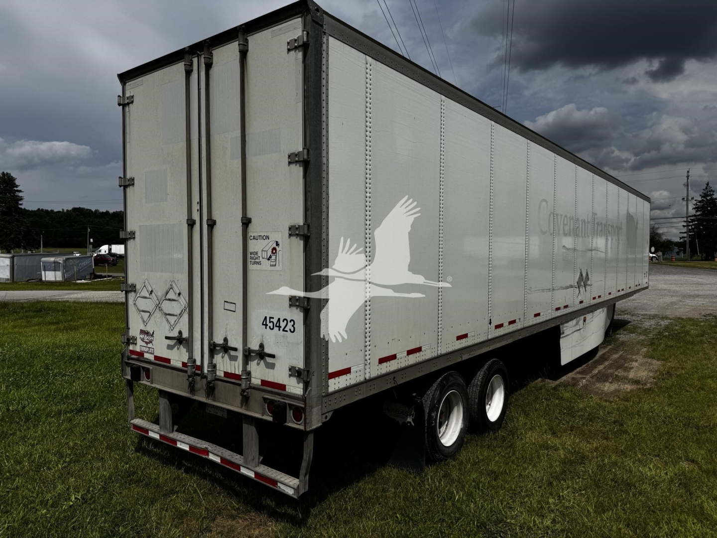 2017 Wabash van trailer showing side and rear with doors, tri-axle wheels, and reflective markings.