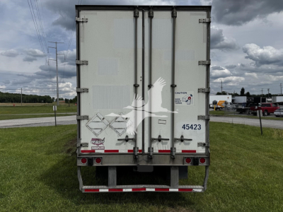 Rear view of a 2017 Wabash van trailer showing double rear doors and various labels and hazard stickers.