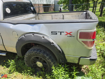 Ford F-150 pickup bed with STX 4x4 badge on the rear quarter panel; extended cab; spare wheel well and dirt on the tailgate area.