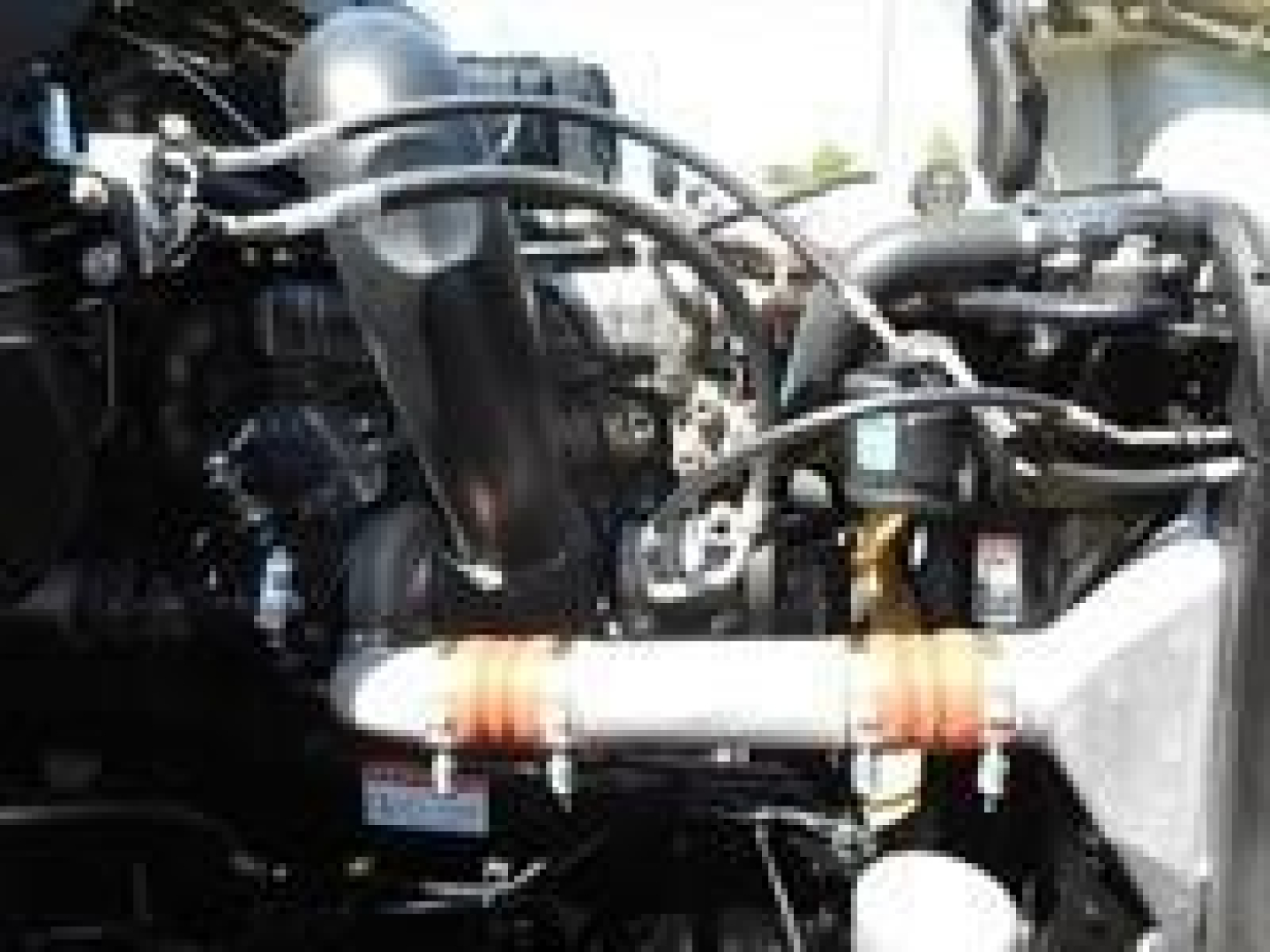 Engine bay of a 2023 Freightliner Cascadia 126 showing hoses, intercooler pipe, and components.