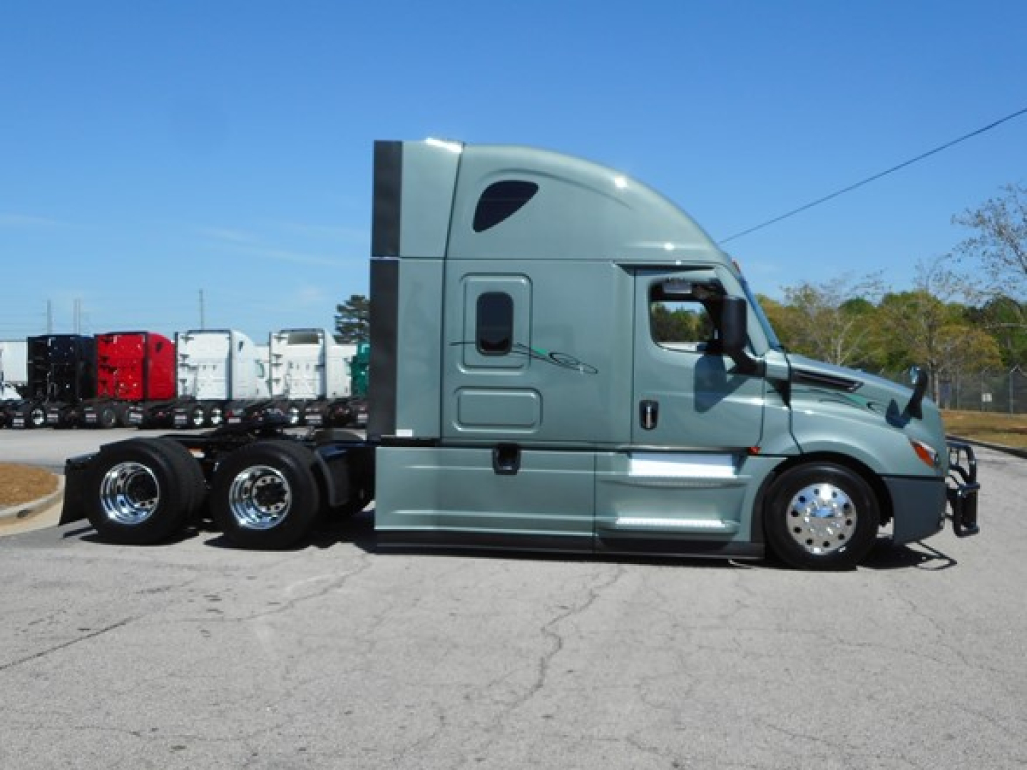 Tractor unit side view showing Freightliner Cascadia 126 sleeper cab with chrome wheels and dual rear axles.