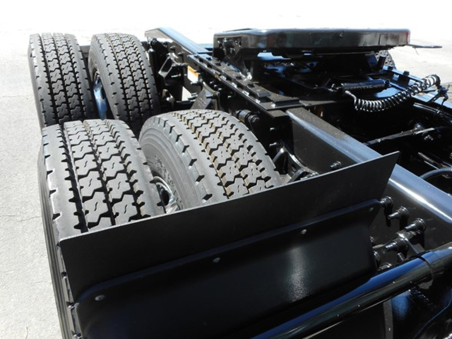 Tractor trailer chassis showing dual rear axles with tires and frame, view of fifth wheel area and suspension components.