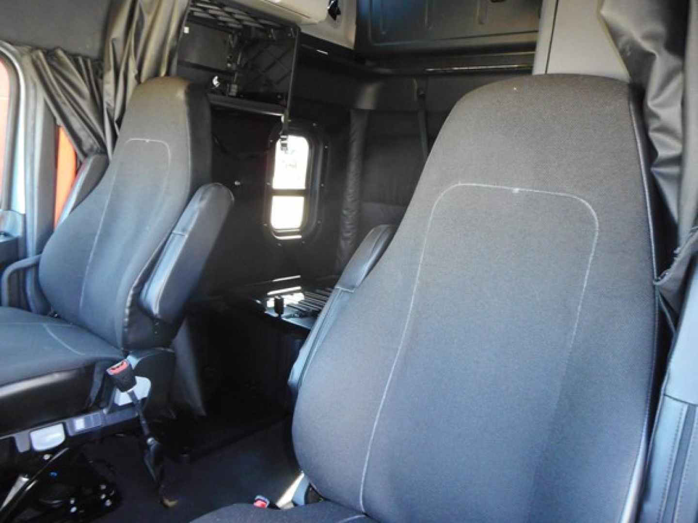 Truck cab interior showing front seats and sleeper area; no legible brand text visible on components.