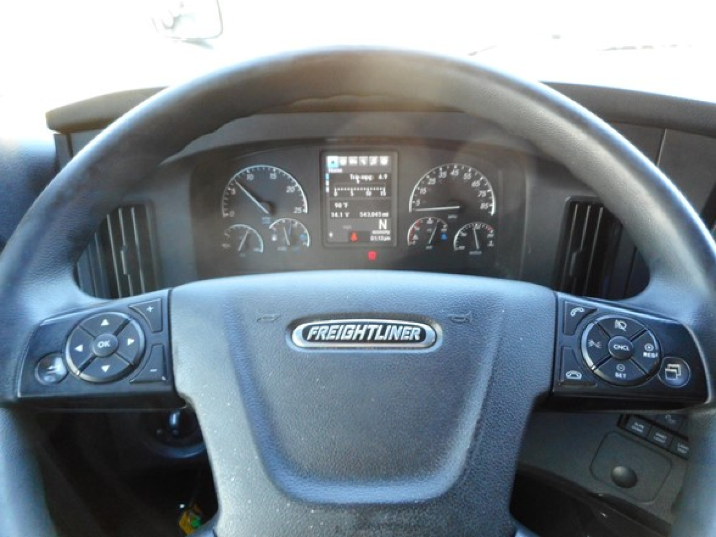 Freightliner Cascadia dashboard and steering wheel with gauges and center display visible.